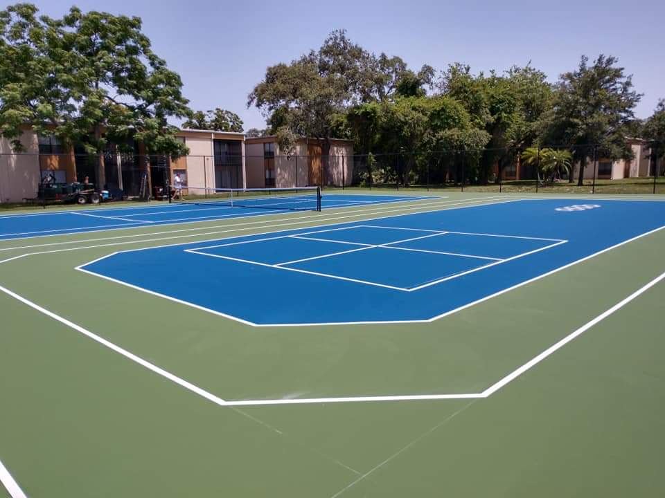 Blue and green pickleball court with a player at the far end