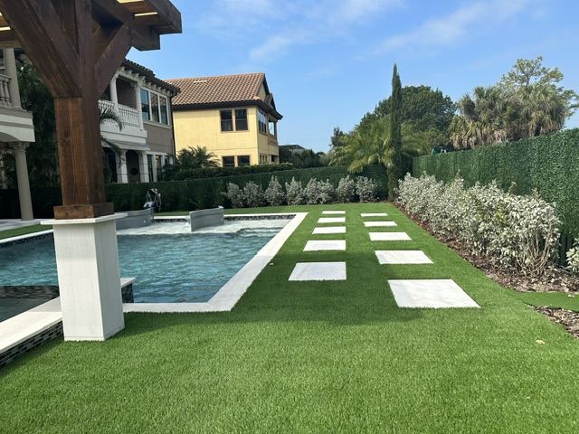 Synthetic turf around a pool with square stepping pavers